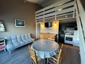 a living room with a table and a loft bed at Rêve de plage in Camiers