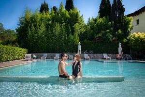 a man and a woman sitting in a swimming pool at The Ziba Hotel & Spa in Peschiera del Garda