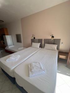 a large white bed with two towels on it at Aphrodite Apartments in Agios Gordios