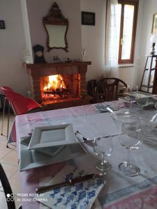 a dining table with wine glasses and a fireplace at La Rosa Selvatica in Ravarino