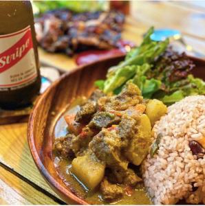 un plato de comida con carne, hortalizas y arroz en Emerald inn at runaway bay en Runaway Bay