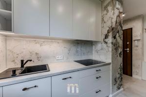 una cocina con armarios blancos y fregadero en Tropical Jungle Apartament, en Otwock