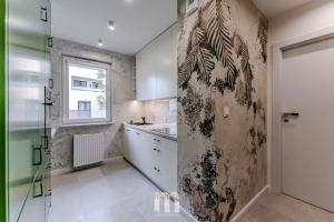 a kitchen with white cabinets and a glass wall at Tropical Jungle Apartament in Otwock