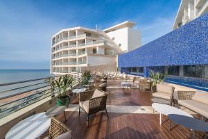 a balcony with chairs and tables and a building at Sesimbra Oceanfront Hotel in Sesimbra