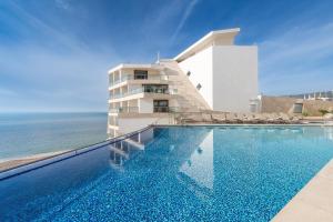 a swimming pool in front of a building with the ocean at Sesimbra Oceanfront Hotel - Preferred Hotels and Resorts in Sesimbra