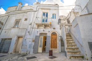 an old white building with stairs and a door at Casa Coppaiaia - Spaziosa e luminosa nel centro storico in Martina Franca