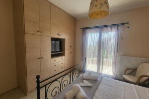 a bedroom with a bed and a television and a window at Βίλα Χαρά in Eretria