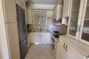 a kitchen with white cabinets and a black refrigerator at Βίλα Χαρά in Eretria