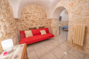 a red couch in a room with stone walls at Casa Coppaiaia - Spaziosa e luminosa nel centro storico in Martina Franca +8 photos