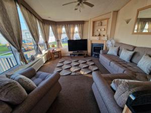 a living room with couches and a flat screen tv at Jasmine's Retreat - Pet friendly, Ingoldmells in Ingoldmells