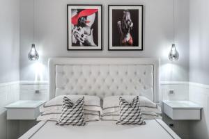 sypialnia z białym łóżkiem z 3 obrazami na ścianie w obiekcie Rome55 - Piazza di Spagna w Rzymie