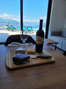 a bottle of wine and cheese on a wooden table at Bay View Village - Villa Eléanore 2 in Herceg-Novi