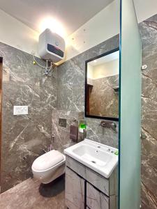 een badkamer met een wastafel, een toilet en een spiegel bij Wonderstays in Amritsar