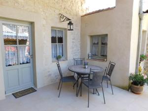 een patio met een tafel en stoelen naast een deur bij Maison Jules Goux in Mirmande