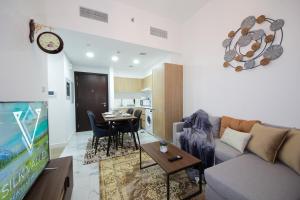 uma sala de estar com um sofá, uma televisão e uma mesa em Silk Valley - Furnished 1bhk With Pool And Gym em Abu Dhabi