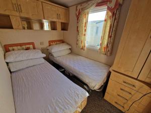 two beds in a small room with a window at Jade's Haven - Pet friendly, Ingoldmells in Ingoldmells