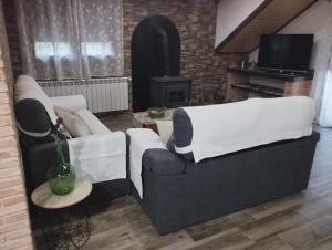 a living room with two white couches and a television at Haza Del Puente in Riópar