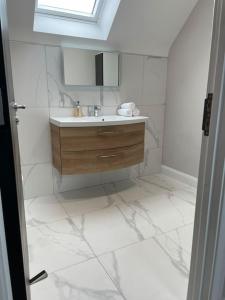 a white bathroom with a sink and a mirror at Belfast Luxury: Spacious 2BR Home Near Stormont in Belfast