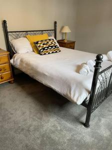 a bed with a black frame and pillows on it at Belfast Luxury: Spacious 2BR Home Near Stormont in Belfast