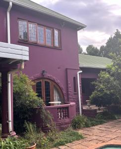 a purple house with a porch at Pebble Fountain Guesthouse in Pretoria