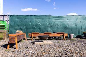 a group of benches and a grill in front of a green fence at Penzion JAAL in Příbor