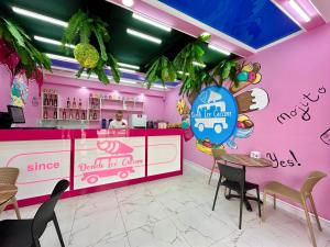 a pink restaurant with a woman behind a counter at Dendi Plaza Hotel in Bukhara