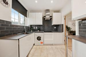 a kitchen with white cabinets and a washing machine at The Grosvenor Residences in London
