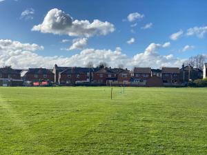 a green field with houses in the background at Cosy Semi-detached House To Stay In West Yorkshire in Heckmondwike