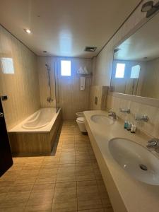 a bathroom with two sinks and a tub and a toilet at Ny Suites in Beirut