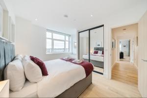 a white bedroom with a large bed and a mirror at Roomspace Serviced Apartments- Syward Place in Chertsey