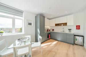 a kitchen with white cabinets and a table and chairs at Roomspace Serviced Apartments- Syward Place in Chertsey