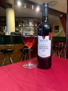 uma garrafa de vinho sentada numa mesa com um copo em Wellness Hotel Várfal em Pécs