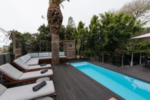 a patio with a palm tree and a swimming pool at The Tree House Boutique Hotel by The Living Journey Collection in Cape Town