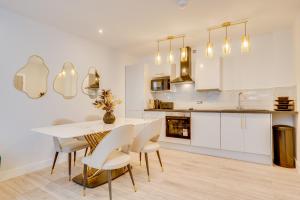 a white kitchen with a white table and chairs at DH APARTS in Leeds