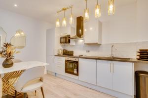 cocina con armarios blancos y mesa blanca en DH APARTS, en Leeds