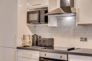 a kitchen with white cabinets and a counter top at DH APARTS in Leeds