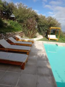 a row of lounge chairs next to a swimming pool at Establecimiento La Soleada suites de campo in La Cumbre