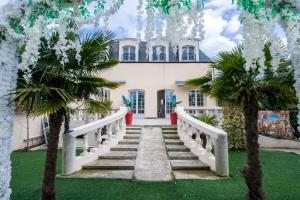 a white house with palm trees in front of it at Appartement Emeraude - Paris à 13 minutes in Deuil-la-Barre