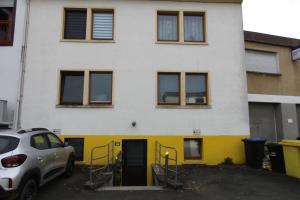 a white and yellow house with a car parked in front at Kleine Wohnung für Singles in Daun