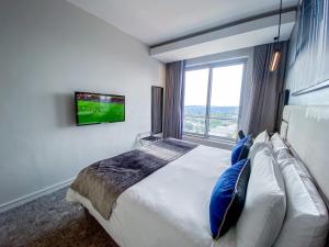 a bedroom with a large bed with a tv on the wall at Cosy Executive Hotel Room (SA) in Johannesburg