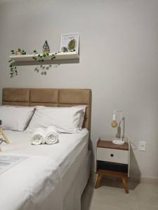 1 dormitorio con 1 cama blanca con mesita de noche y 1 cama sidx sidx sidx sidx en Apartamento amplo cabo frio en Cabo Frío