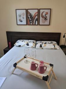 Una cama con dos copas de vino y una bandeja. en Apartamento amplo cabo frio en Cabo Frío