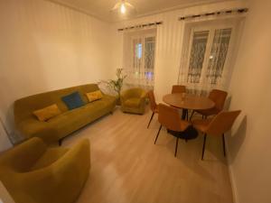 uma sala de estar com um sofá, uma mesa e cadeiras em La Petite Auberge de Strasbourg em Estrasburgo