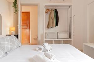 Un dormitorio con una cama blanca con toallas. en Homiday- New Apt- Free Parking- Aeroporto - Ospedale en Pisa