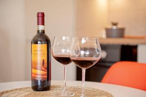 uma garrafa de vinho e dois copos numa mesa em Homiday- New Apt- Free Parking- Aeroporto - Ospedale em Pisa