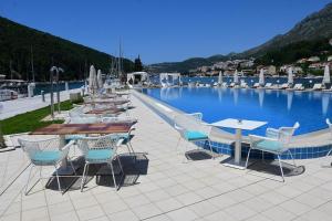 una gran piscina con mesas y sillas junto a ella en Dubrovnik house - Leni, en Komolac