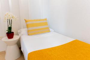 Un pequeño dormitorio con una cama y un jarrón con flores en Hostal Josefina-Gran Vía, en Madrid
