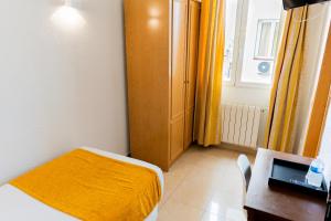 1 dormitorio con cama, mesa y armario en Hostal Josefina-Gran Vía, en Madrid