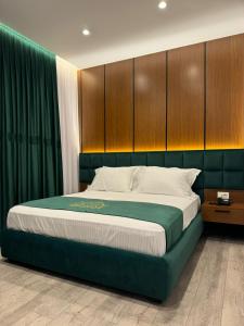 um quarto com uma cama grande e cabeceiras de madeira em Reign Hotel em Vorë