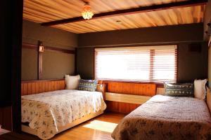 a bedroom with two beds and a window at カフェロッジ Touch Wood in Biei